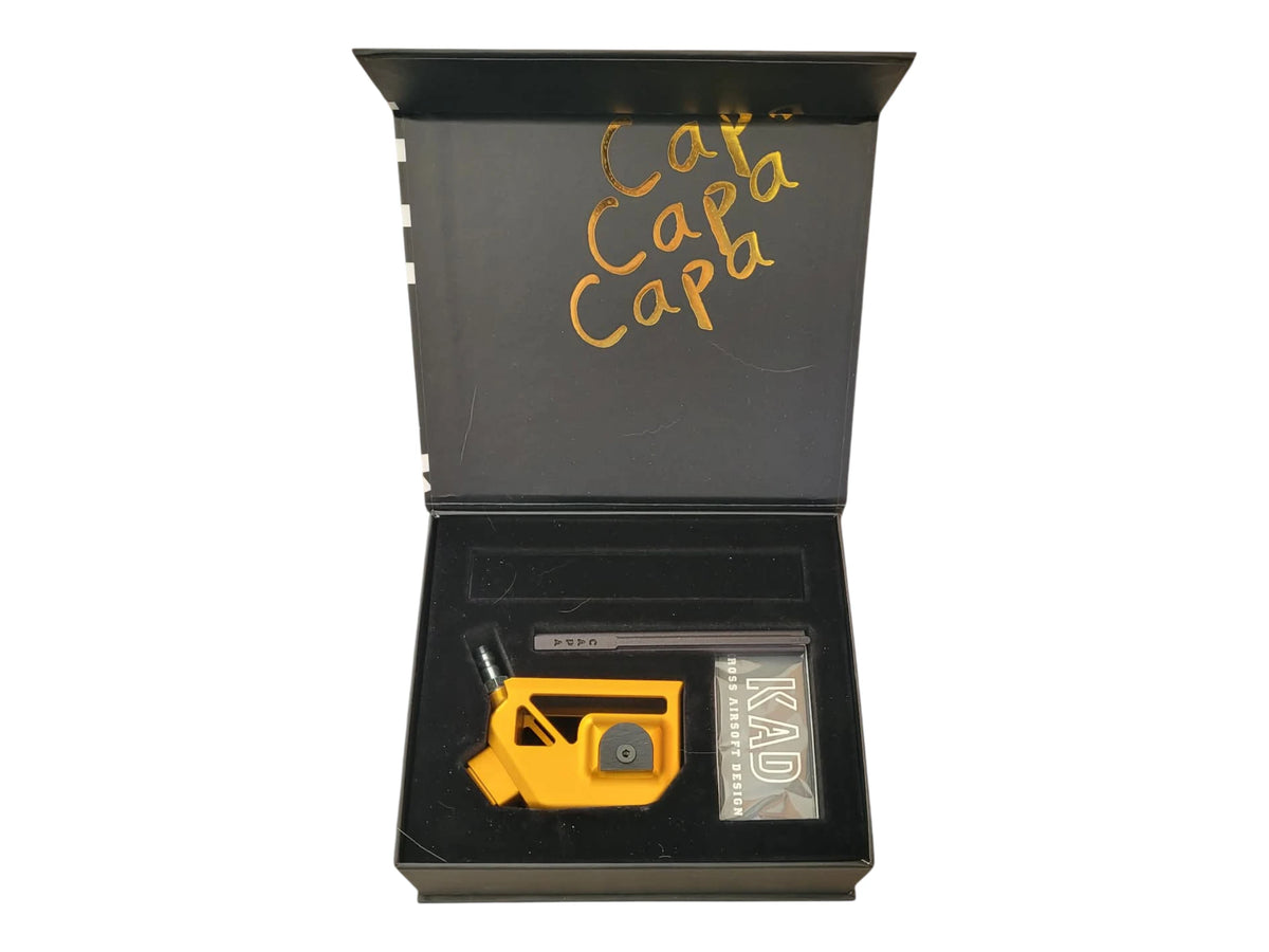Kross Airsoft Design Skelly Hi-Capa adapter in gold, shown in its lined presentation box with a KAD card