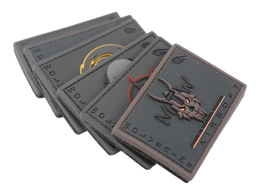 Stack of fanned Wolverine PVC morale patches in grey and tan, the top one showing a horned skull design